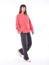 Buzo color salmón, de corte holgado y cuello con abertura en forma de V.