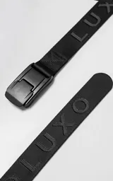 Cinturón negro de tela con hebilla metálica de cierre a presión y letras en relieve.