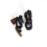 Sandalias de cuero negro con tiras anchas, hebillas doradas y tacón de madera.