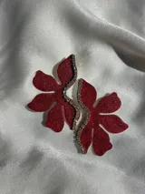 Par de aros con forma de flor roja brillante y detalle de strass plateado en el centro. Cierre a presión de acero inoxidable.