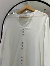Blusa blanca de manga larga regulable, con escote en pico y botones frontales.