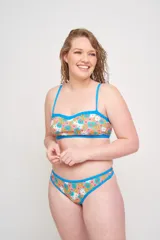 Top de bikini con escote corazón y estampado floral en tonos rosa, naranja, amarillo y blanco. Tiene breteles finos regulables y contorno inferior en color celeste.