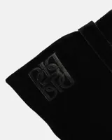 Bota alta de cuero gamuzado color negro con tacón cuadrado y diseño estilizado.