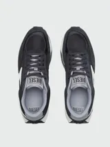 Zapatillas deportivas Diesel modelo S-Tyche D, color negro con detalles en blanco y gris. Presentan una silueta de running retro con paneles de malla y gamuza, entresuela gruesa blanca y suela exterior negra. El logo lateral es una 'D' estilizada en blanco.