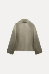 Abrigo corto color verde oliva, de cuello solapa y manga larga. Cuenta con bolsillos delanteros de vivo y cierre frontal cruzado con botones.