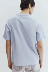 Remera celeste de punto de algodón pesado, corte holgado, cuello redondo ribeteado, hombros caídos y bajo recto.
