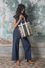 Bolso estructurado de cuerpo rectangular y diseño vertical, confeccionado en cuero croco metalizado champagne gold con detalle central en cuero liso tono olive shadow. Incorpora asas cortas para hombro y correa desmontable regulable para llevar tipo bandolera.