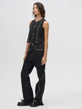 Pantalón de jean azul de tiro alto y corte oxford con apliques metálicos en bolsillos y laterales.