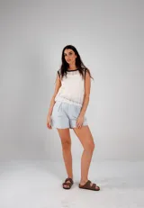 Blusa blanca de crochet calado, sin mangas y con cuello redondo con ribete negro.