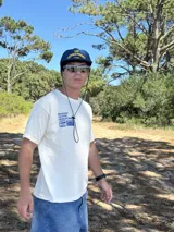 Remera beige de manga corta con estampado gráfico en azul en la espalda que incluye el texto "BROKERS GRAPHIC RESEARCHING" y "THE NEW WAVE BROKERS".