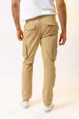 Pantalón cargo color beige, de corte ajustado, con bolsillos laterales con fuelle y cierre de botón a presión.