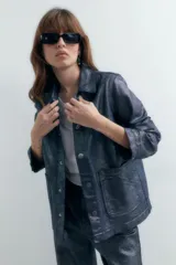 Sobrecamisa de denim metalizado color azul con cuello clásico, cierre frontal con botones, bolsillos de parche en el pecho y mangas largas.