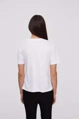 Remera blanca con estampado de hojas de ginkgo biloba en tonos naranja, beige y gris.