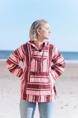 Buzo estilo mexicano con capucha, de tejido grueso a rayas horizontales en tonos rosa y borgoña.