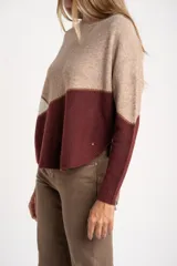 Sweater de tejido de punto con diseño de bloques de color en tonos beige, blanco roto y bordó. Presenta cuello redondo y mangas largas.