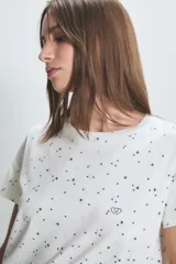 Conjunto de pijama blanco con estampado de lunares negros, compuesto por una remera de manga corta y un pantalón largo.