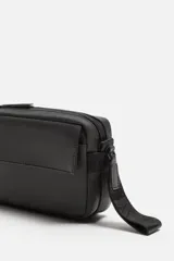 Bandolera negra de acabado engomado, con compartimento principal con cierre de cremallera y bolsillo interior de rejilla con cremallera. Bolsillo frontal con solapa y botones a presión. Asa de hombro ajustable y extraíble.