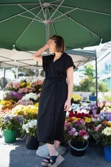 Vestido negro de lino con cuello y manga corta, corte a la cintura con lazo ajustable.