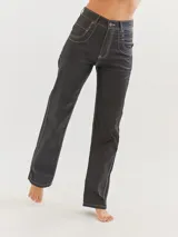 Pantalón jean recto color negro con costuras blancas contrastantes.