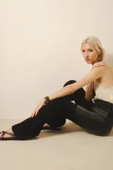 Pantalón jean negro de tiro medio, calce ajustado y pierna acampanada desde la rodilla.