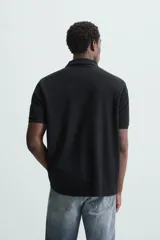 Polo de piqué color crudo, corte regular fit, cuello solapa con cierre de botonadura y mangas cortas.