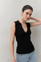 Top negro tejido sin mangas con escote en V y cuello tipo solapa.