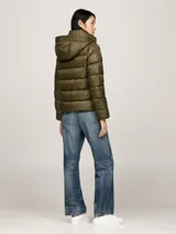 Campera puffer verde militar de Tommy Hilfiger, con capucha ajustable, cierre frontal con cremallera, dos bolsillos delanteros con botón a presión y parche con el logo de la marca en la manga.