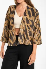Kimono con estampado abstracto en tonos marrón, beige y negro. Tiene mangas 3/4 y bolsillos laterales.
