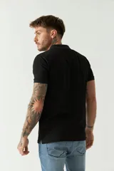 Remera polo negra de manga corta con cuello clásico, cierre de botones, bolsillo en el pecho y logo estampado.