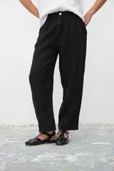 Pantalón negro de lino, de corte ancho y tiro alto, con pinzas en la cintura y bolsillos laterales.