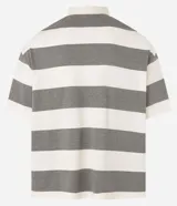 Camisa polo oversized con cuello abotonado, mangas cortas y diseño a rayas horizontales en tonos crema y gris. Presenta estampados con texto en el pecho.