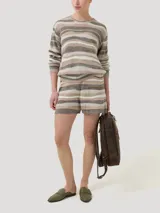 Sweater de punto con cuello redondo y mangas largas. Presenta un diseño de ondas horizontales en tonos beige, marrón y gris.