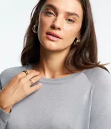 Suéter de punto color gris plateado, con cuello redondo y mangas largas. Presenta puños y bajo acanalados.