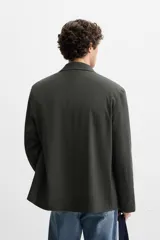 Blazer regular fit color gris oscuro, confeccionada en tejido con estructura. Cuello con solapas de muesca y manga larga. Bolsillos de solapa en cadera. Cierre frontal de botonadura.