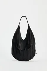 Bolso negro tipo shopper con flecos en el cuerpo y asa de hombro. Tiene bolsillo interior con cremallera y cierre con imán.