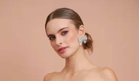 Aros tipo caravana grandes con forma de moño, completamente cubiertos de strass plateado.