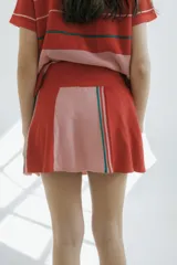 Minifalda de punto color crudo con paneles laterales en azul marino y rayas rojas y blancas. Cintura elástica con cordón ajustable.