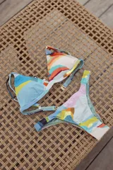 Conjunto de bikini turquesa con corpiño triangular de corte fijo, breteles regulables y almohadillas desmontables, y bombacha vedetina con frunce elástico en los costados.