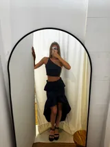 Pollera de tafeta color azul marino con diseño asimétrico de tipo high-low y volados. Presenta una cintura entallada y gran volumen en el ruedo.