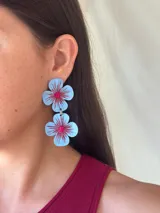 Aros colgantes con forma de flor celeste con centro rosa y detalles en rojo.