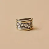Anillo ancho de plata y oro con diseño de laberinto griego.