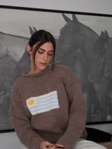 Sweater tejido a mano color marrón con cuello redondo y diseño de la bandera de Uruguay en el frente.