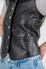 Chaleco color arena de cuero ovino, con cuello en V y cierre frontal con botones.