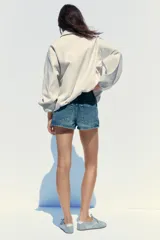 Chaqueta bomber color crudo con cuello solapa, manga larga con puño elástico interior, bolsillos laterales, forro interior, bajo acabado en elástico y cierre frontal con cremallera.