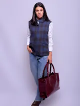 Chaleco azul con diseño a cuadros, cuello alto y cierre frontal con un botón.