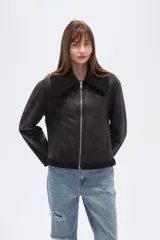 Campera negra de estilo aviador, confeccionada en material tipo gamuza o suede, con cuello y forro de corderito (shearling) negro. Presenta cierre frontal metálico y puños y ruedo con terminación de corderito.