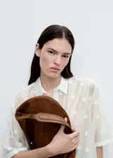 Camisa blanca semitransparente con bordado de flores blancas, de manga corta y cuello camisero.