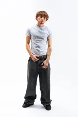 Pantalón de jean azul desgastado, corte mega baggy, con bordado dorado en el bolsillo trasero y botones personalizados.