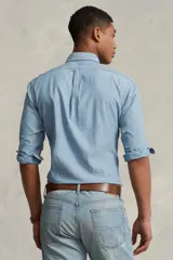 Camisa de hombre marca Polo Ralph Lauren, de manga larga, color celeste claro, confeccionada en tela chambray de algodón. Tiene cuello abotonado y logo bordado en el pecho.