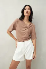 Remera de modal color marrón claro, de manga corta, con cuello asimétrico y detalle de nudo con frunces.